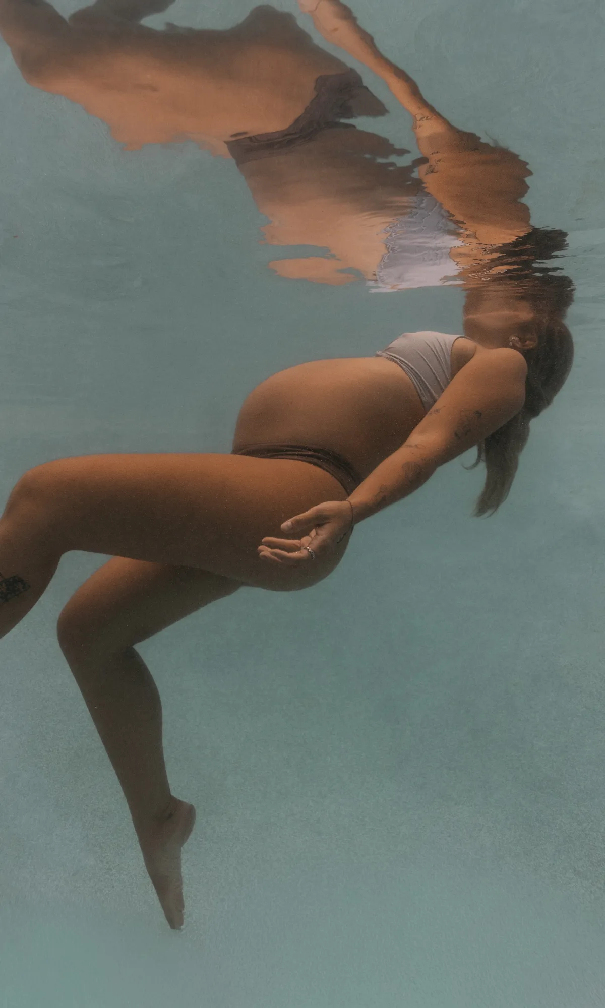 Pregnant woman floating gracefully underwater in crystal clear turquoise Curaçao waters