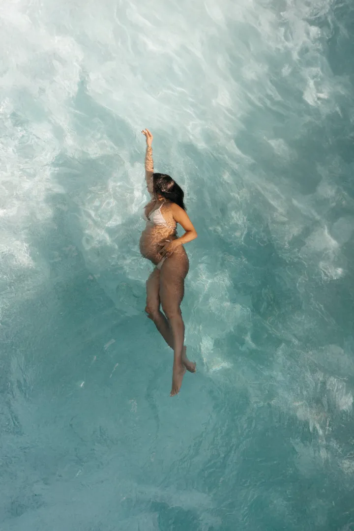 Underwater maternity photography session in Curaçao showing pregnant woman floating in crystal clear turquoise waters