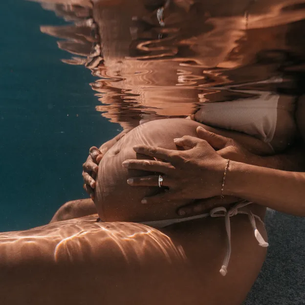 Artistic underwater maternity photography in Curaçao capturing surface reflections and light patterns in crystal waters